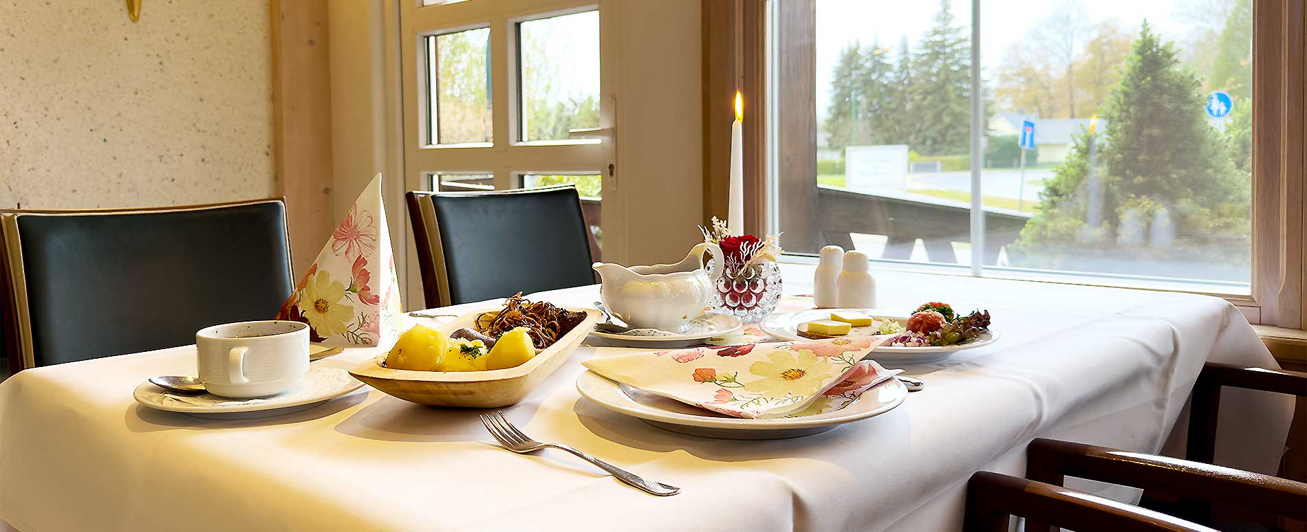 gedeckter Tisch im Restaurant am Fenster mit Kerzenlicht und angerichteter Schlachteplatte