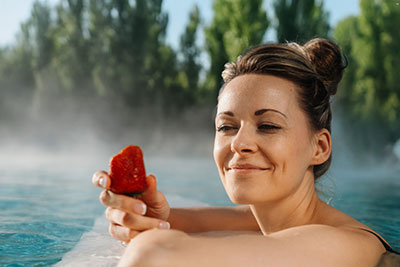 Aktion Erdbeerwellness in der Spreewald Therme Burg Frau im Wasser der Spreewald Therme hält eine rote Erdbeere in der Hand